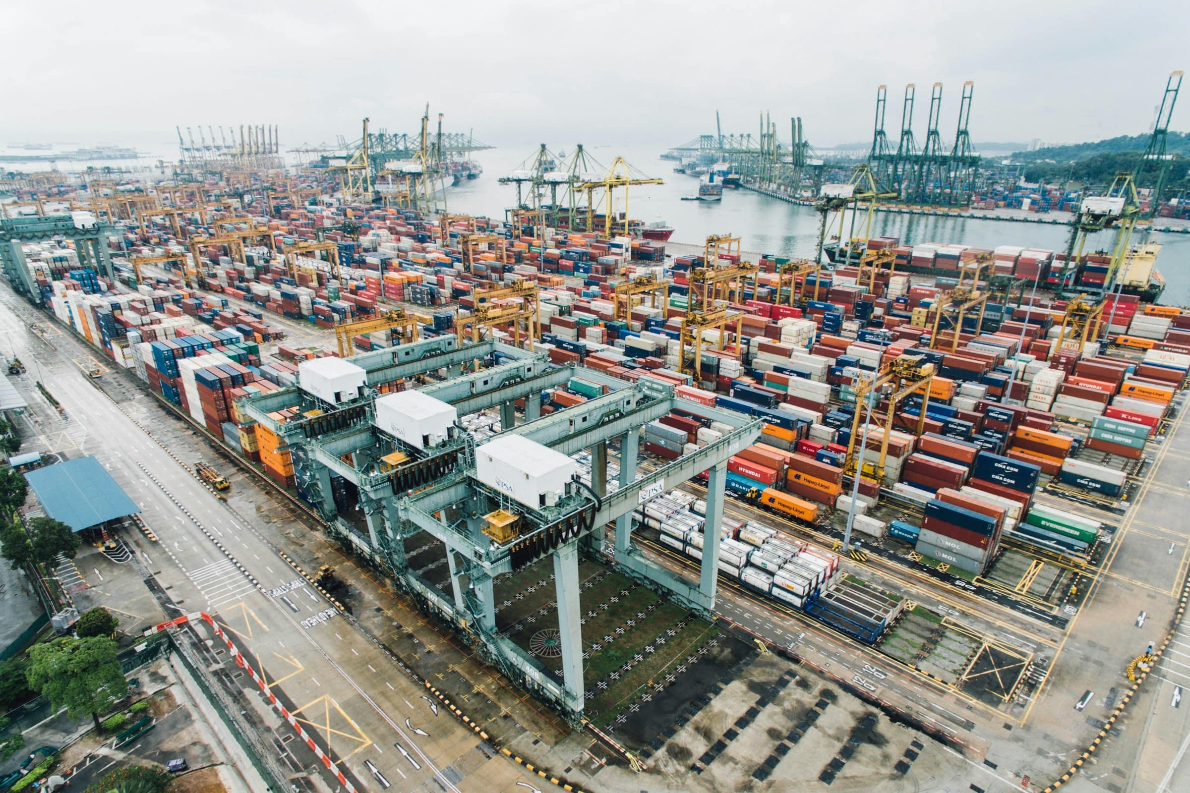 Aerial view of a container terminal with stacked containers and gantry cranes.